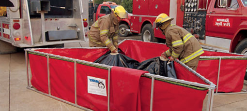Firefighters folding up a Husky folding frame tank