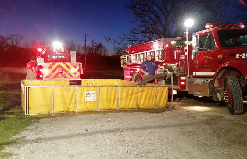 A firefighter preps to put away a folding frame tank, while the husky quick dump makes fast work of getting rid of the remaining water.