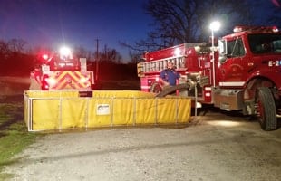 A firefighter preps to put away a folding frame tank, while the husky quick dump makes fast work of getting rid of the remaining water.
