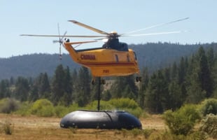 A Helicopter dropping water into a Husky self supporting tank for a rural water shuttle operation