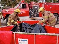 Firefighters folding a Husky folding frame tank using Easy Lift Handles