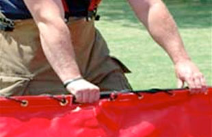 Firefighter folding up a folding frame tank