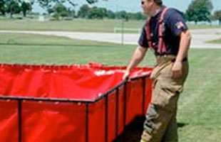 Firefighter folding up a folding frame tank
